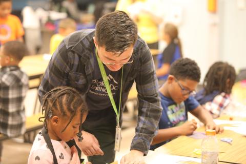 A community Center worker helps a student with their project