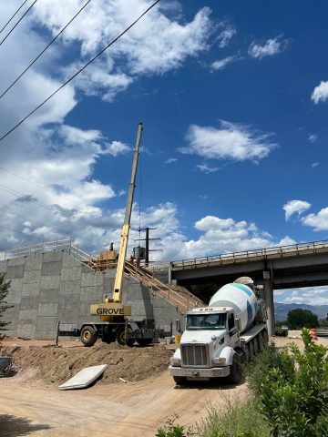 Work is being done on the bridge during the day, A concrete truck is backed up near the bridge.