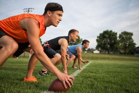 Men line up on the field to get ready for a flag football play