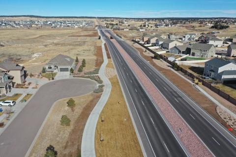 The new Black Forest Road looking north toward the bridges crossing Cottonwood Creek, with the multi-use sidewalk and trail to the left of the roadway.