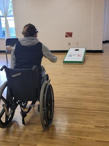 A resident in the TRP Ability Awareness program plays cornhole in their wheelchair.