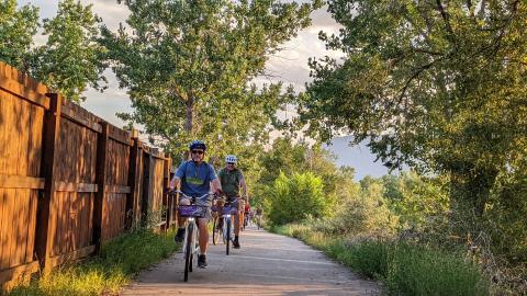 a group of bike riders on an urban trail. They are riding on the right side of the trail leaving the left side open for for passing and people going the opposite direction.