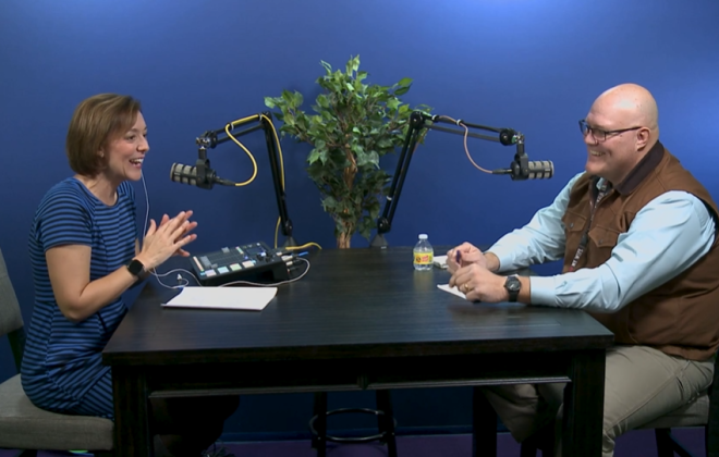 a woman and a man at a table talking into microphones