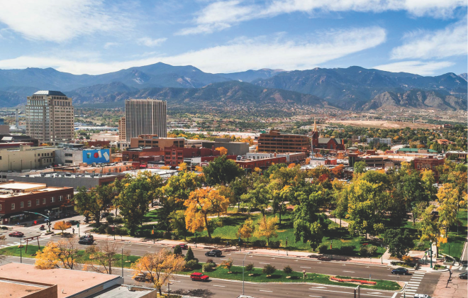 aerial view of acacia park. downtown building and mountains in the background. Some trees have golden leaves.